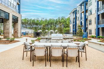 An outdoor patio area with a table and chairs and a grill
